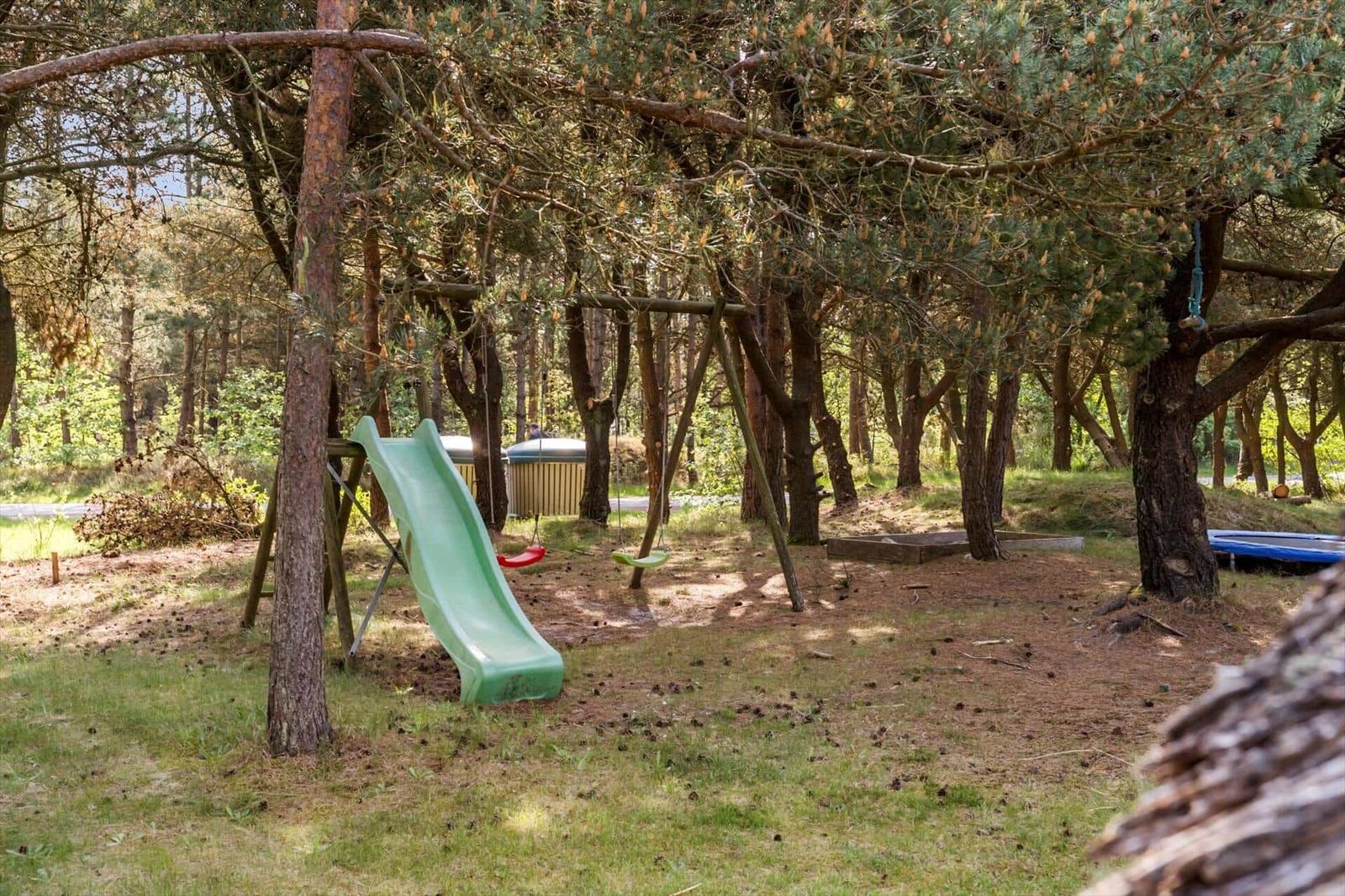 Spielplatz mit Rutsche und Schaukel unter Bäumen