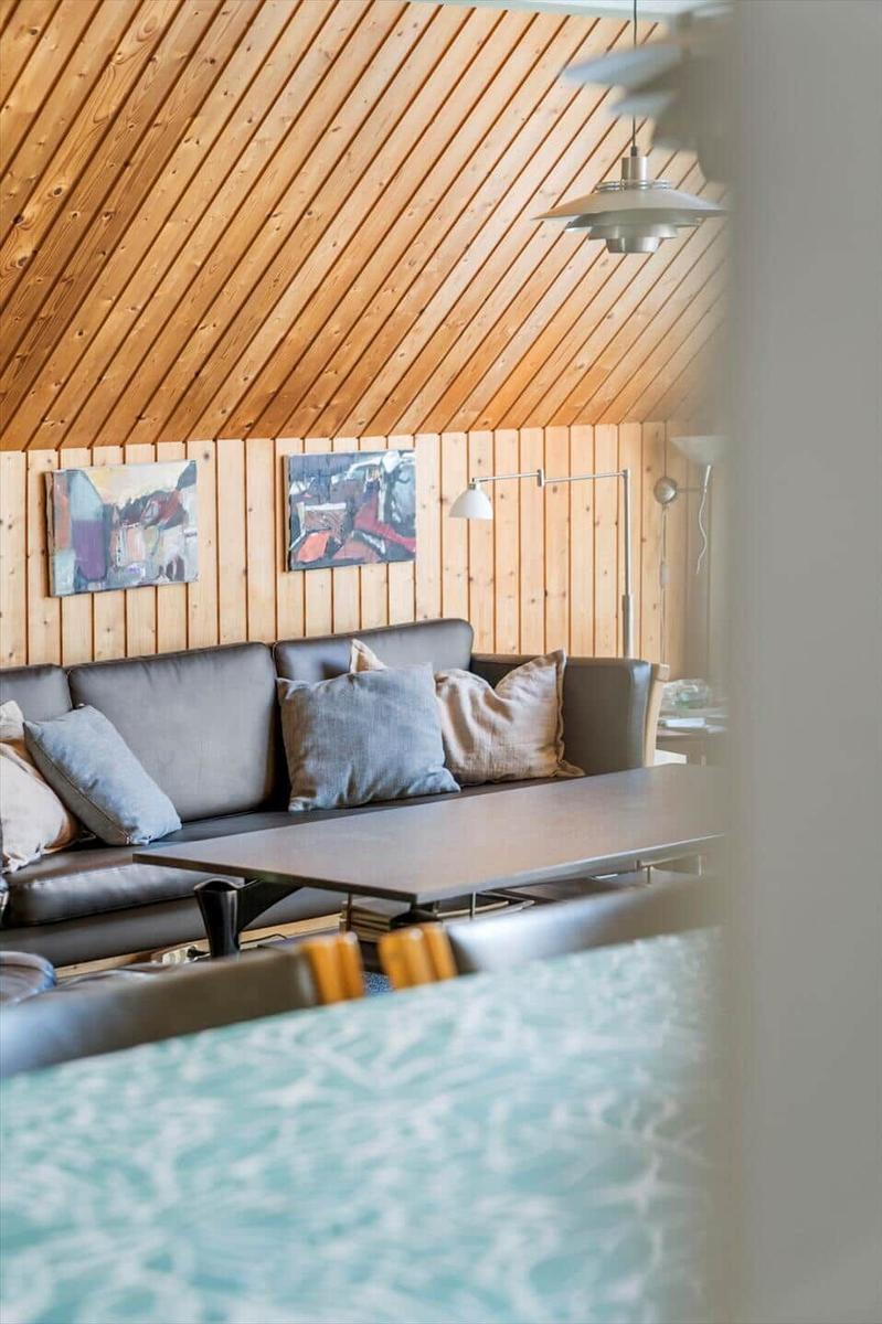 Wohnzimmer mit Sofa, Tisch und Holzwand. Decke aus Holzdielen.