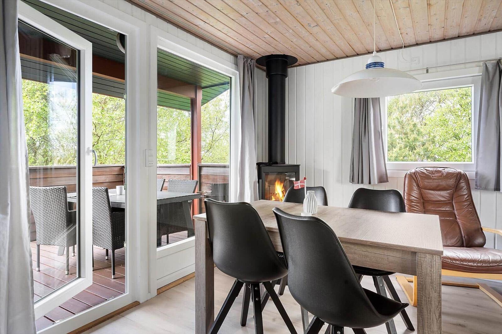 Esszimmer mit Tisch, Stühlen und Kamin. Durchgang zur Terrasse mit Sitzgelegenheit.