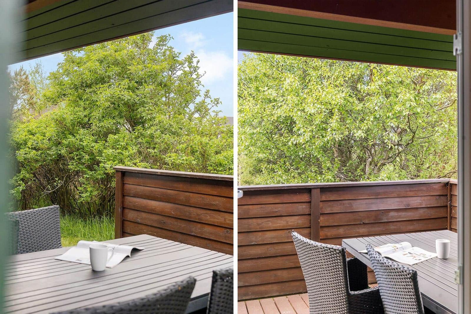 Terrasse mit Tisch und Stühlen, Blick auf grüne Bäume und Sträucher.