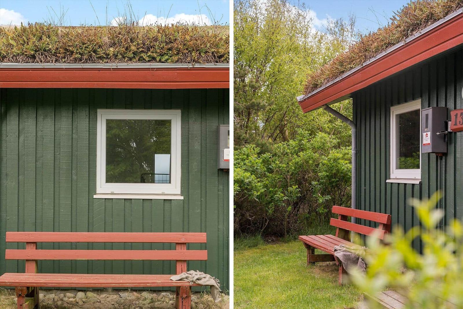 Grünes Holzhaus mit grüner Dachdecke und roter Bank im Garten