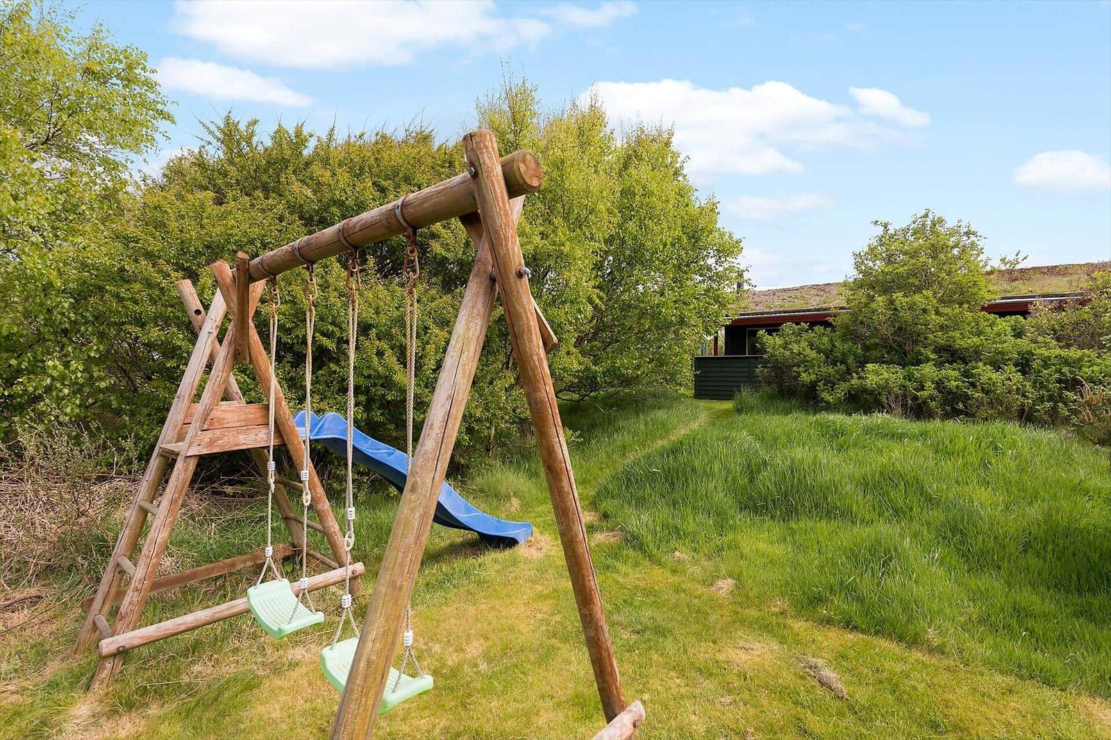 Holzschaukel mit Rutsche im grünen Garten