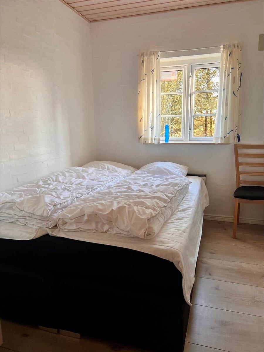 Ein Schlafzimmer mit einem Bett, einem Fenster und einem Stuhl.