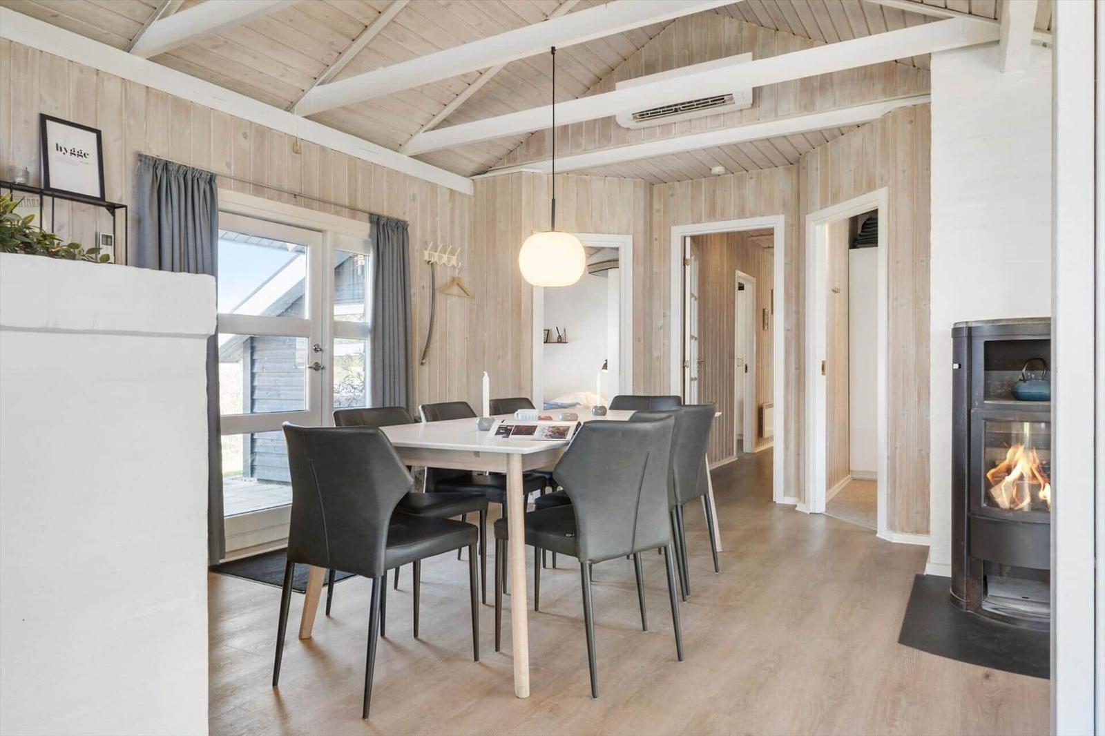 Essbereich mit Tisch, Stühlen und Kaminofen. Holzwände und Decke.
