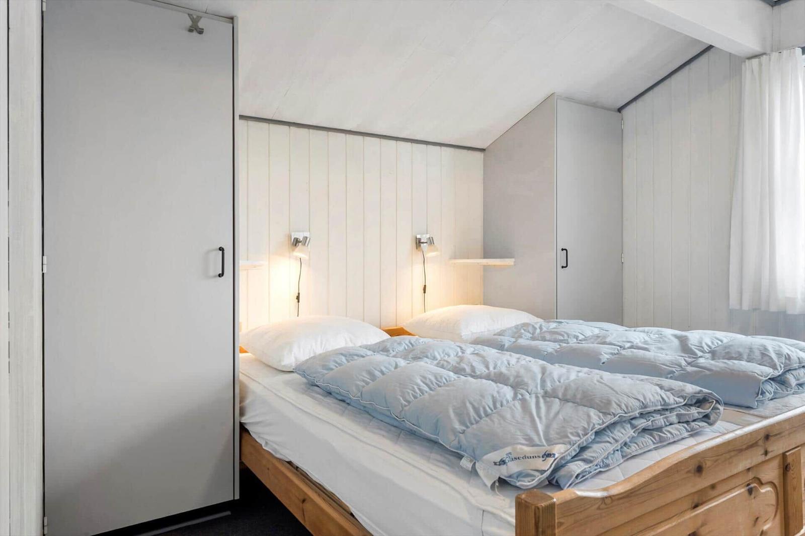 Schlafzimmer mit Bett, Nachttisch und Schränken an den Wänden.