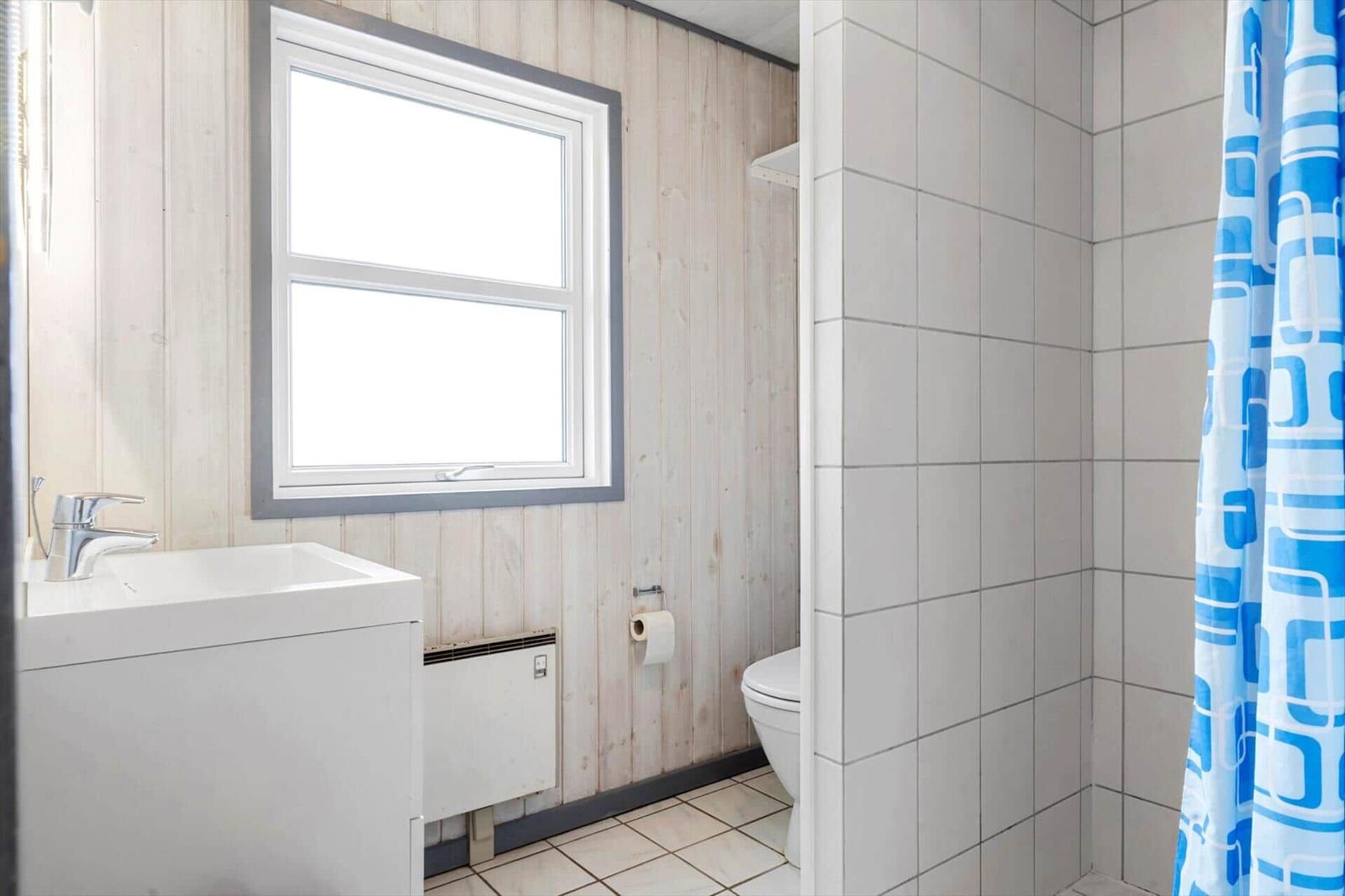 Badezimmer mit Waschbecken, Toilette und Dusche mit blauem Vorhang.