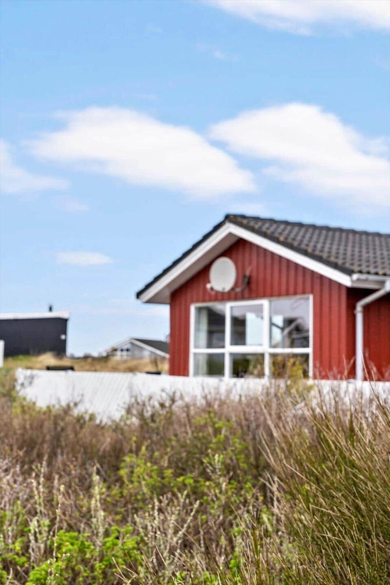 Rotes Haus mit großem Fenster und Satellitenschüssel. Hintergrund: blauer Himmel und Gras.