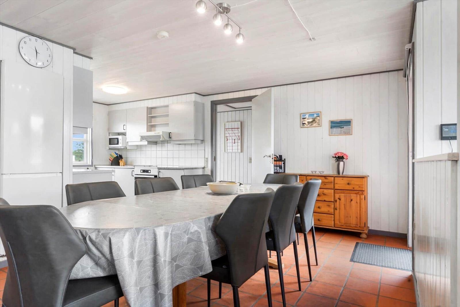 Essbereich mit Tisch und Stühlen, Küchenzeile und Holzschrank an der Wand.