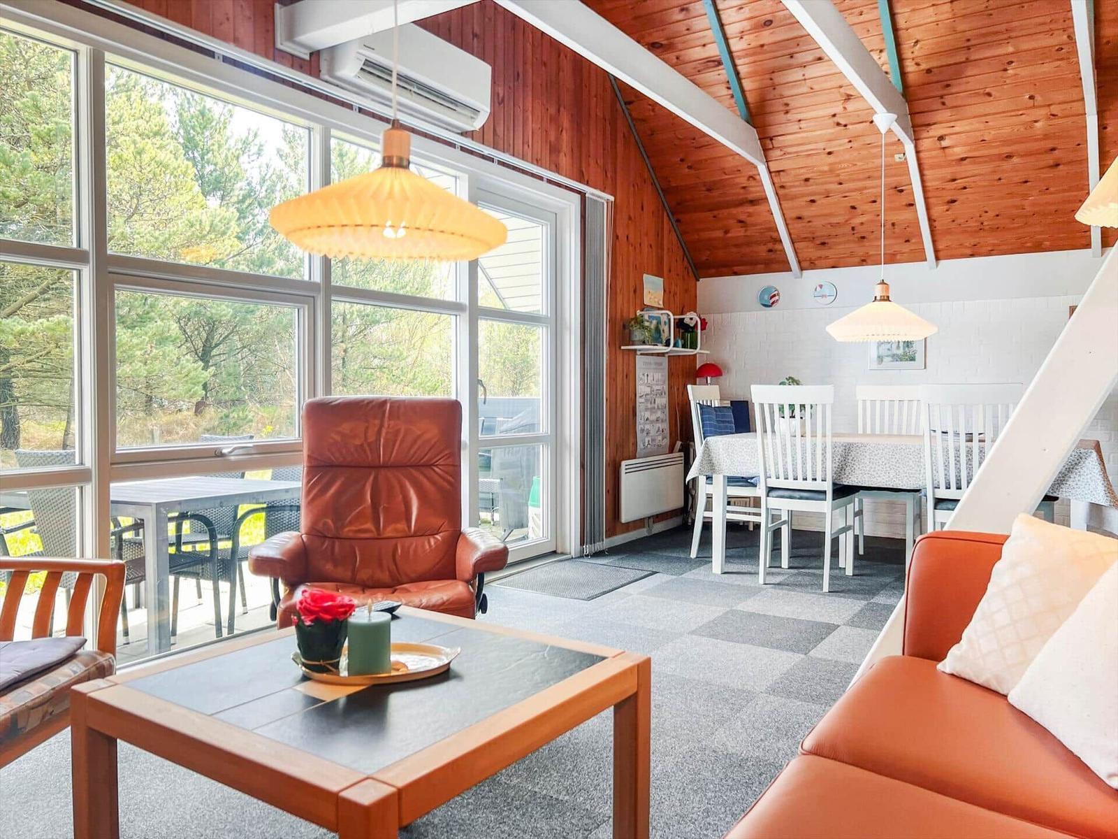Living and dining area with wooden ceiling, windows, and brown seating.
