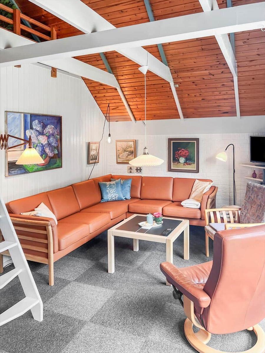 Living room with brown sofa, wooden ceiling, and wall paintings