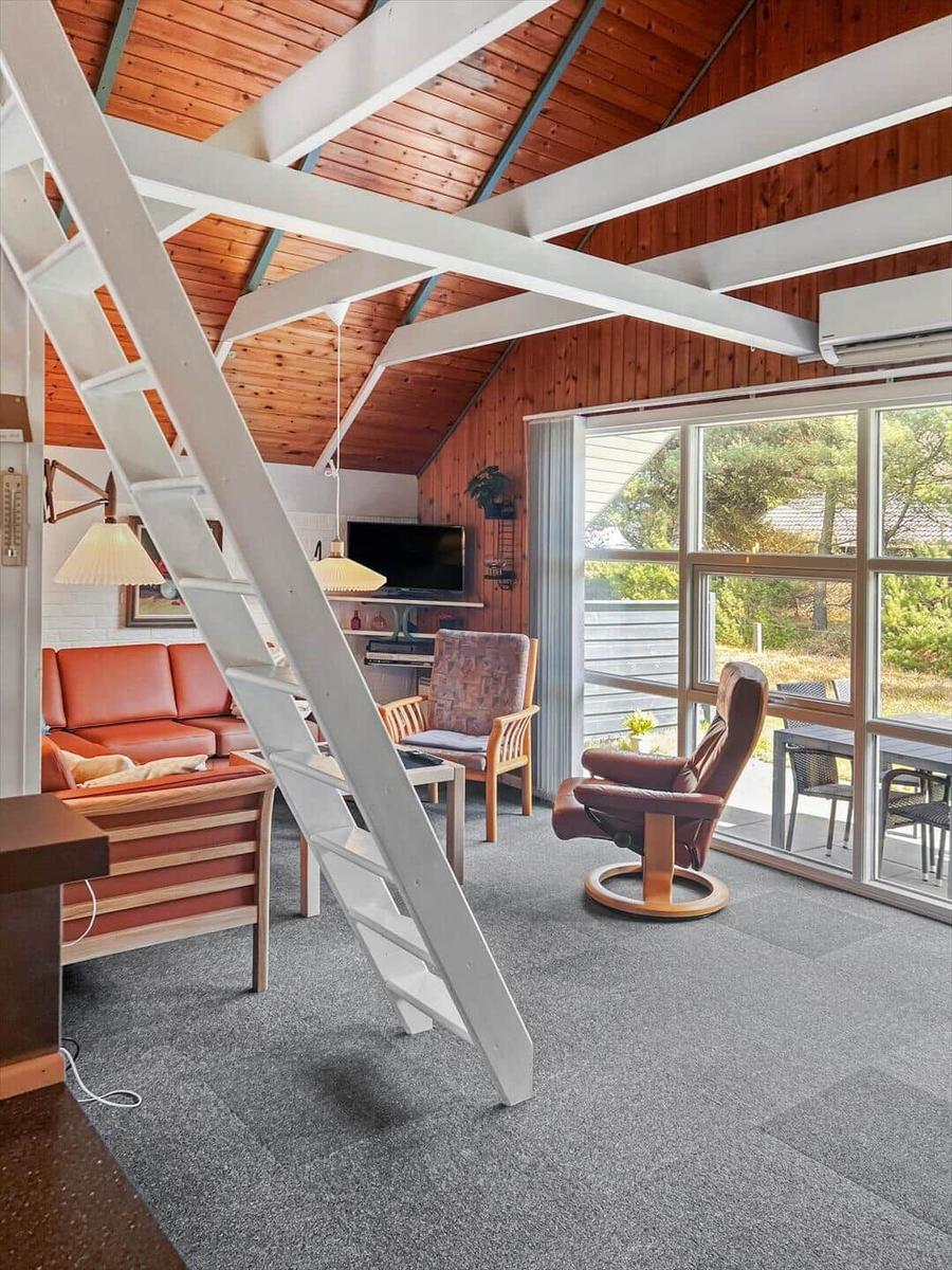 Living room with wooden ceiling, staircase, and large window to terrace.