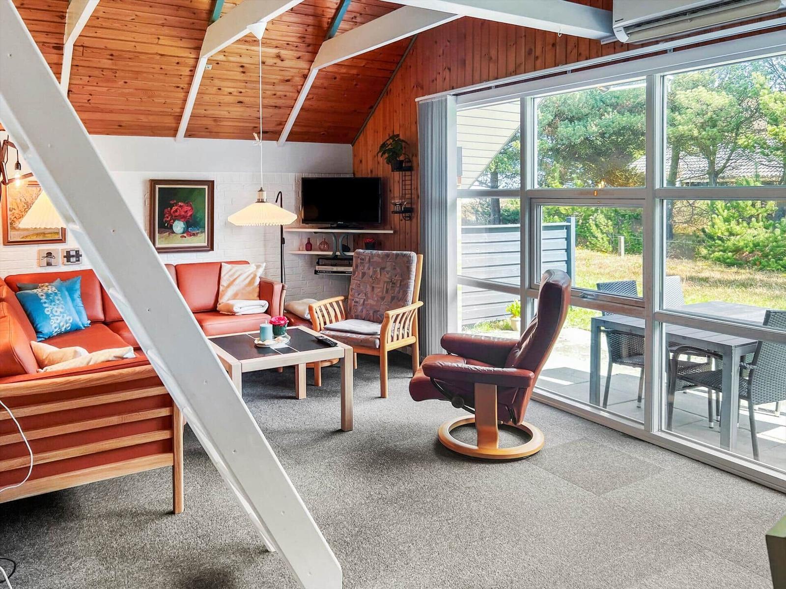 Living room with sofa, armchair, and glass door to terrace.