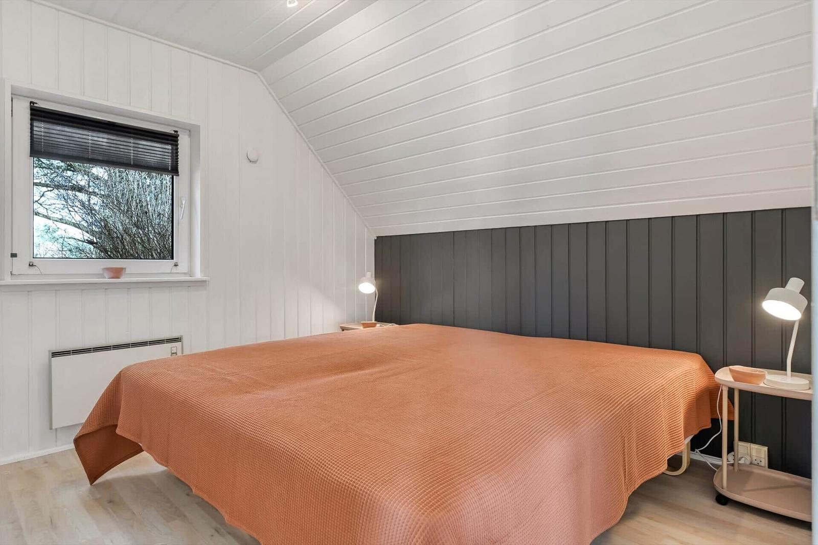 Schlafzimmer mit Bett, Fenster und Nachttischen.