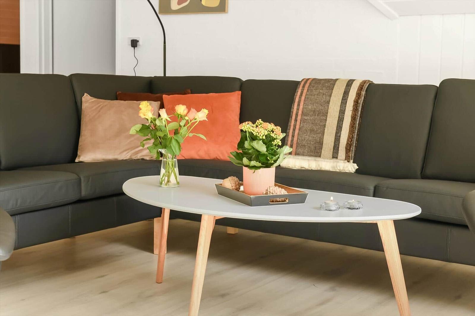 Ein Wohnzimmer mit einem grauen Sofa, einem weißen Tisch und Blumen.