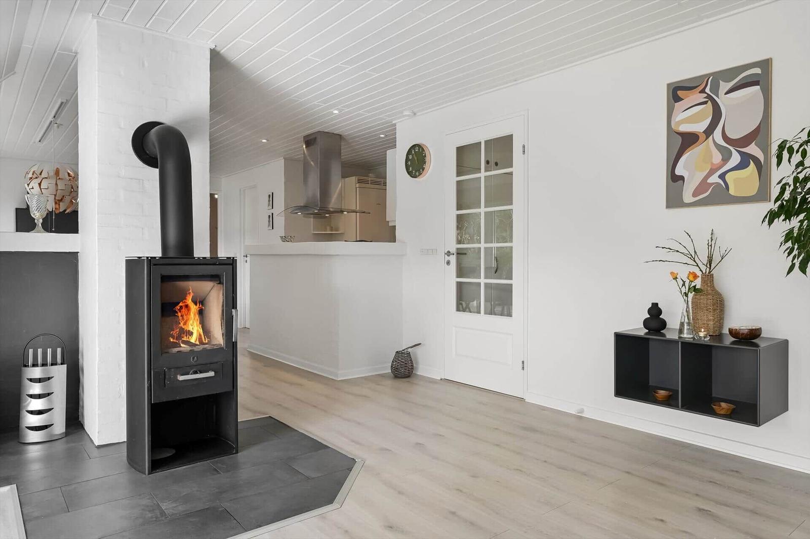 Kaminofen mit Flamme, weiße Wände, Holzboden und moderne Einrichtung.