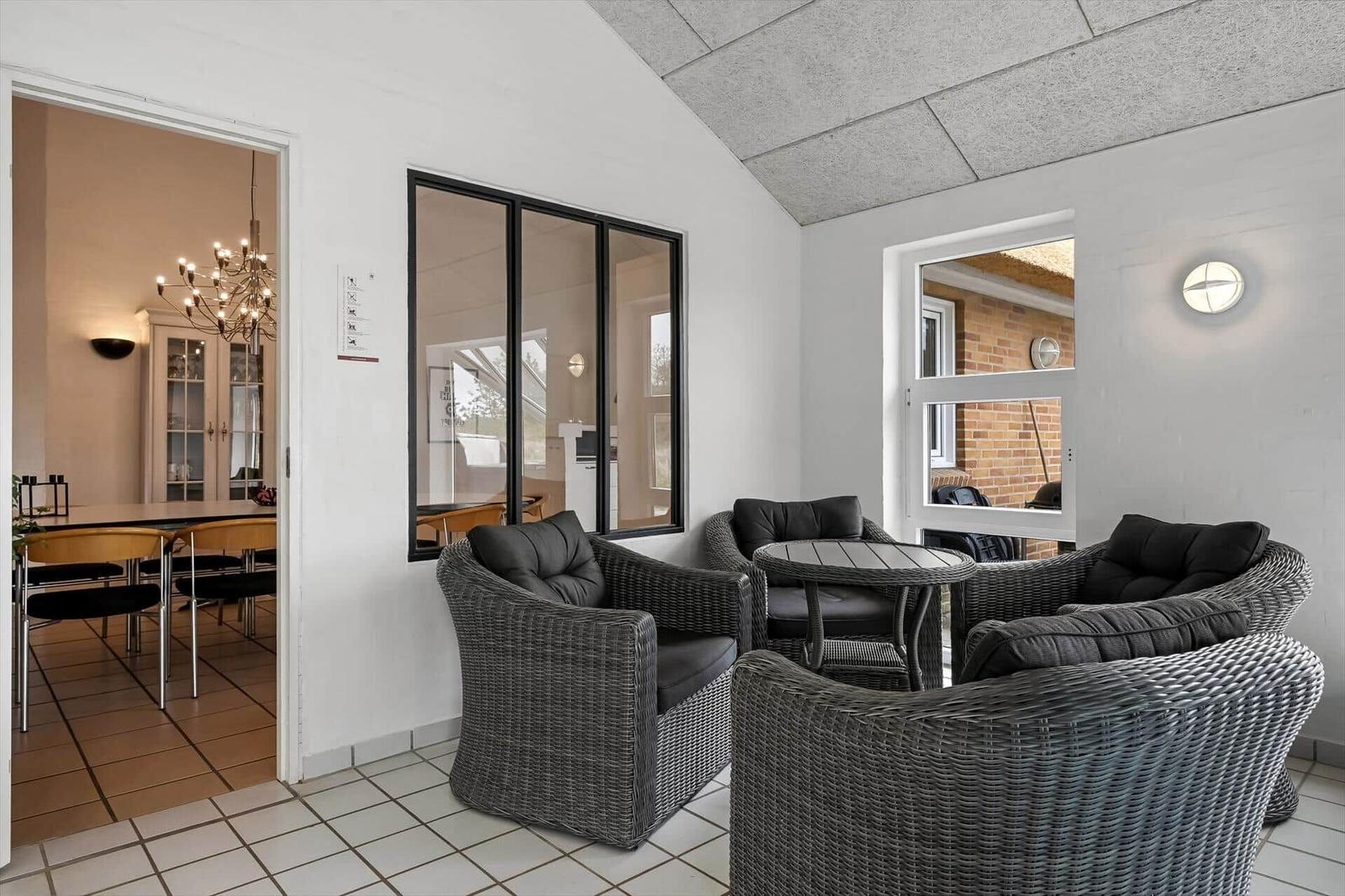Raum mit grauen Rattan-Sofas und Tisch. Durchgang in Essbereich mit Kronleuchter.