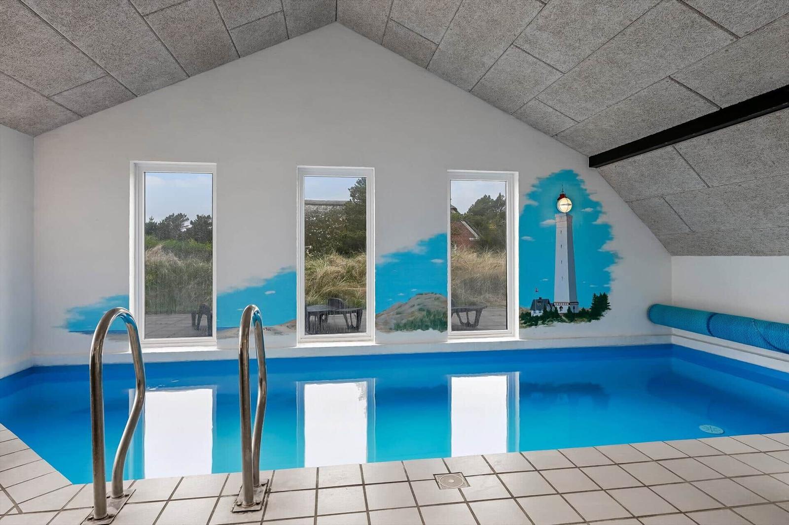 Indirektes Bad mit Pool, Fenstern und Leuchtturm-Malerei an der Wand.
