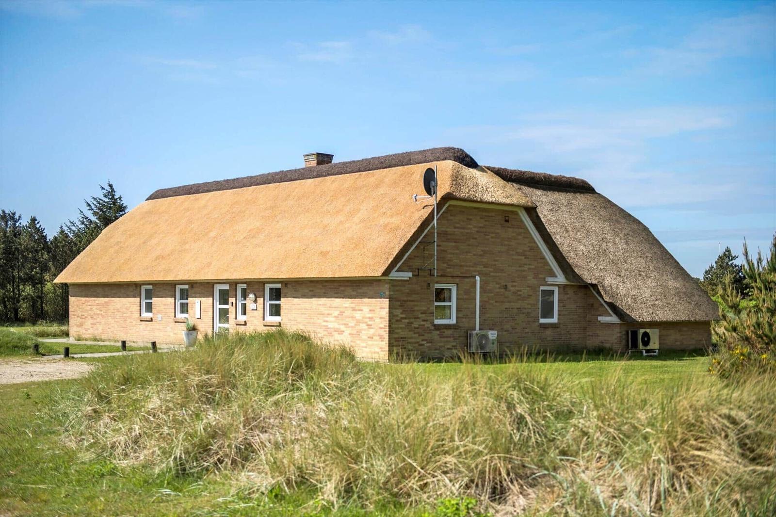 Haus mit strohgedecktem Dach und Backsteinfassade im Grasland.