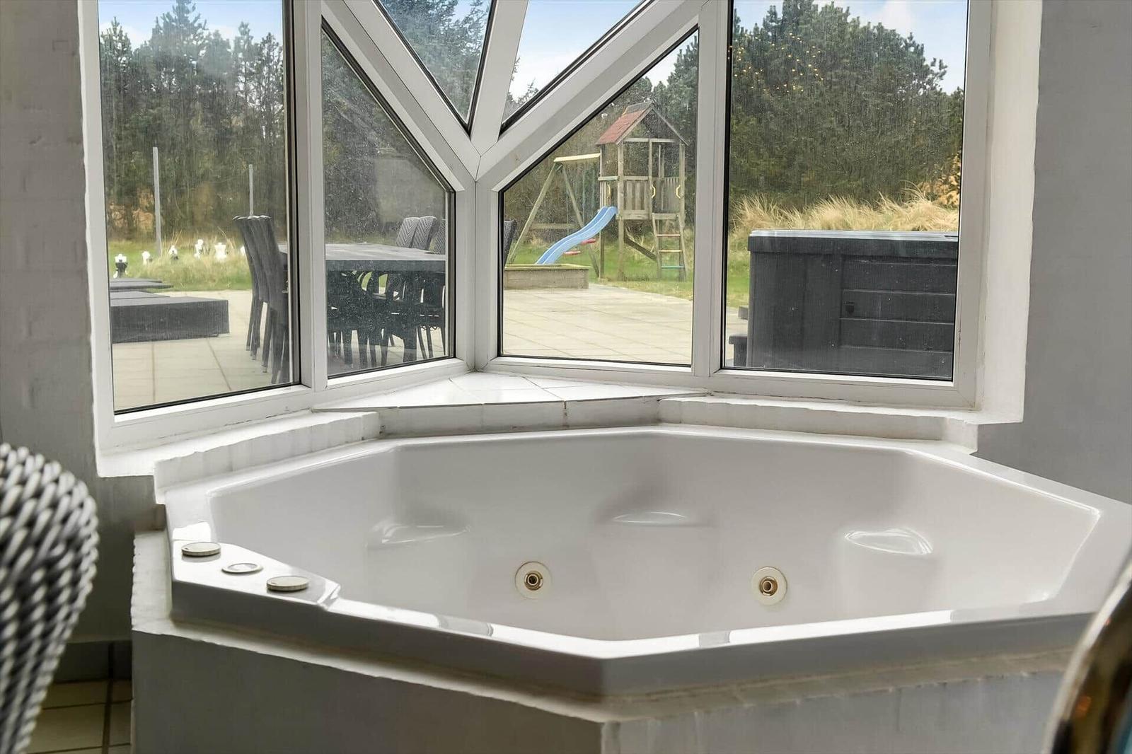 Eckbadewanne mit Blick auf Garten und Spielplatz.