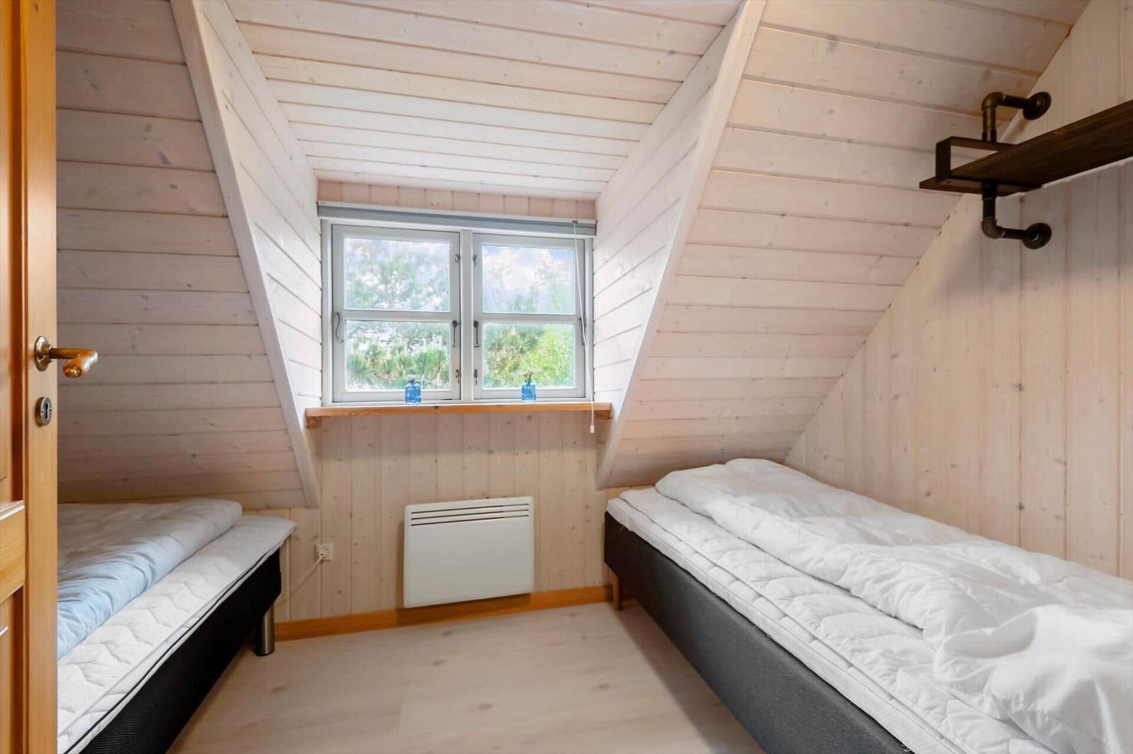 Zimmer mit zwei Betten, Holzwand und Fenster. Heizkörper unter dem Fenster.