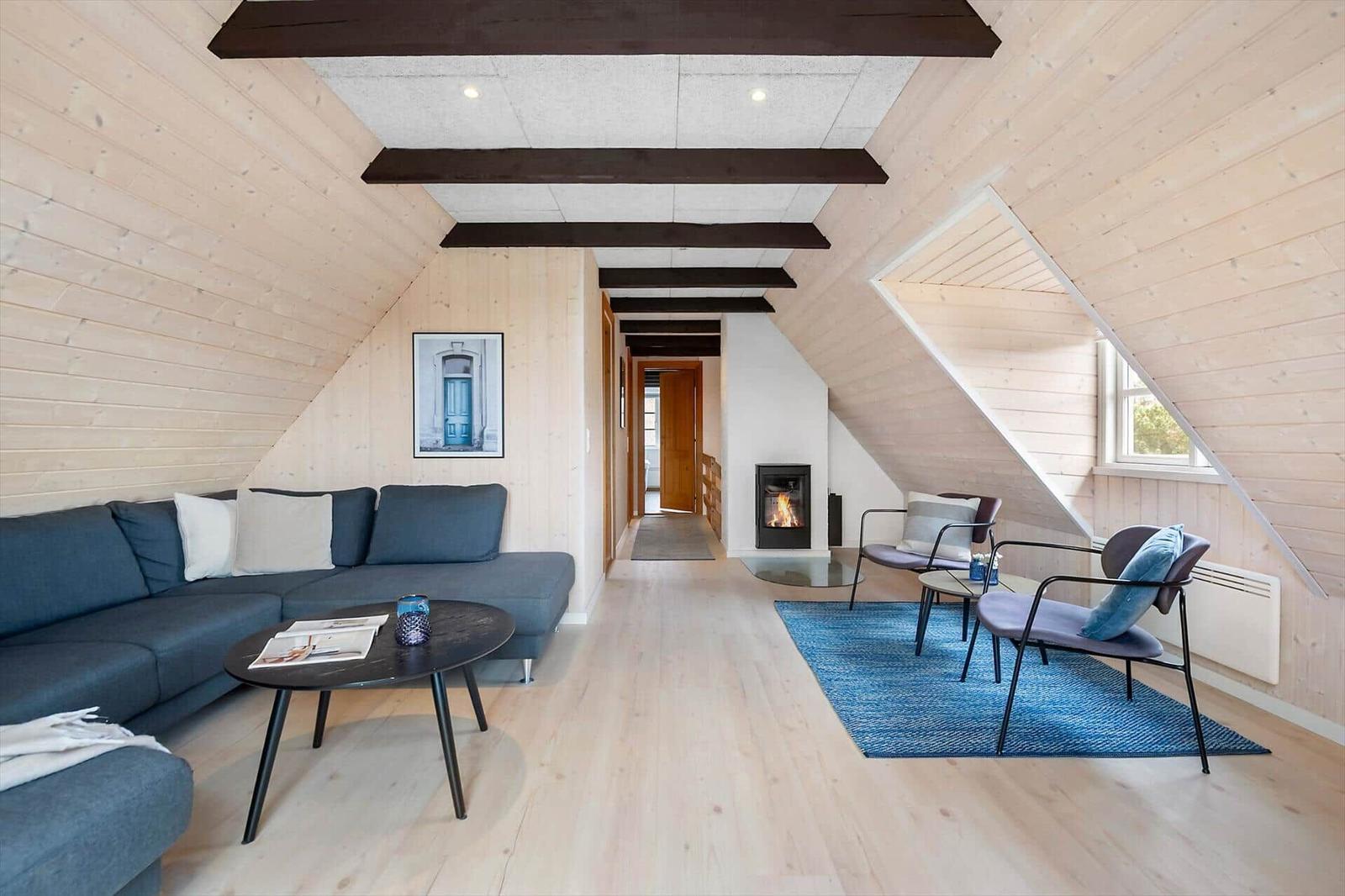 Wohnbereich mit Sofa, Sesseln, Kamin und Holzwand