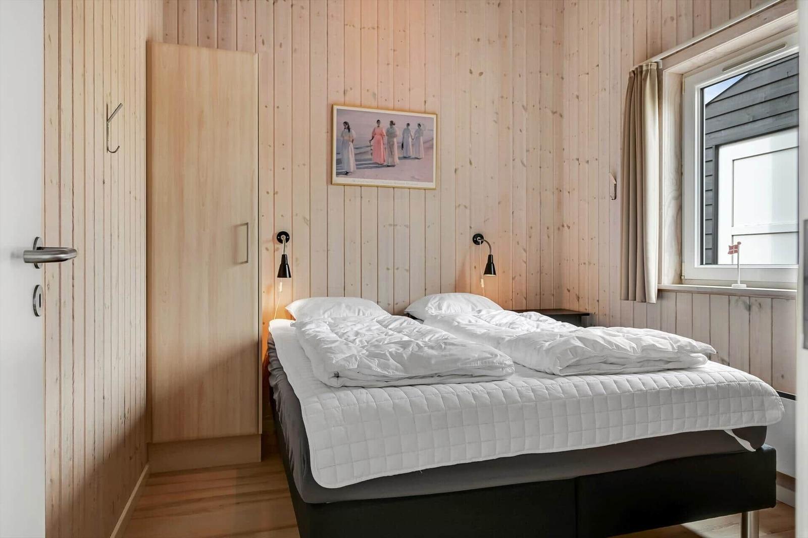 Schlafzimmer mit Holzwand, Bett und Fenster
