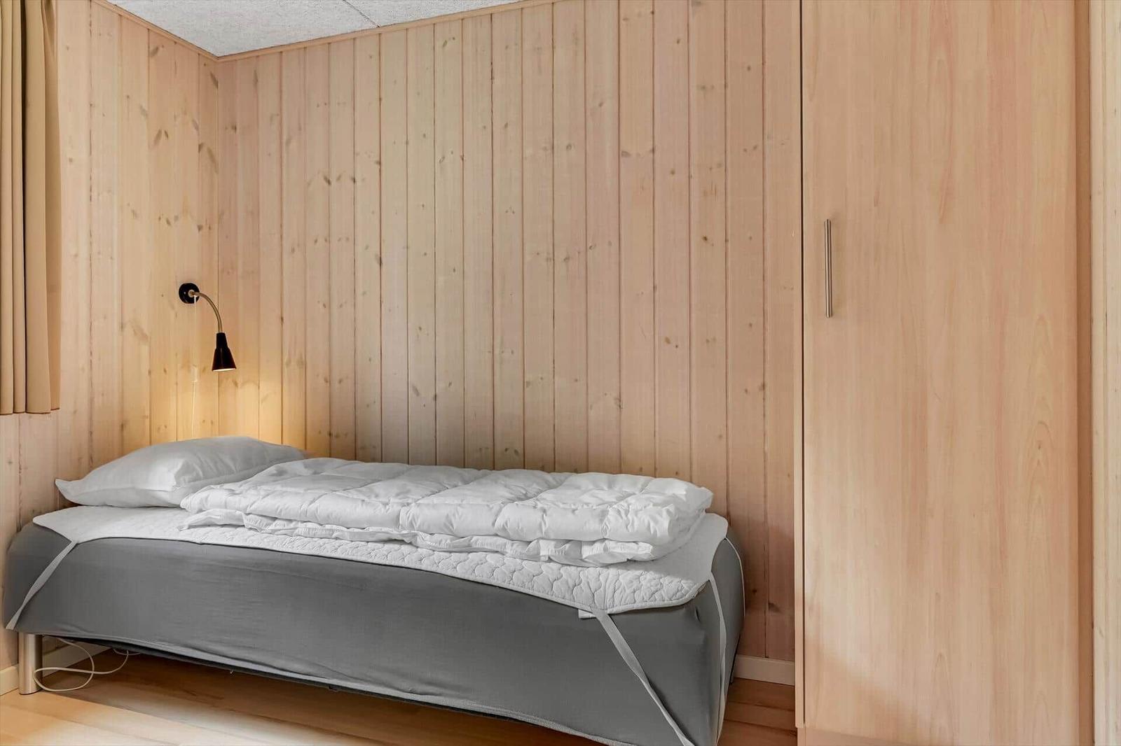 Ein Schlafzimmer mit Holzwand, Bett und Kleiderschrank.
