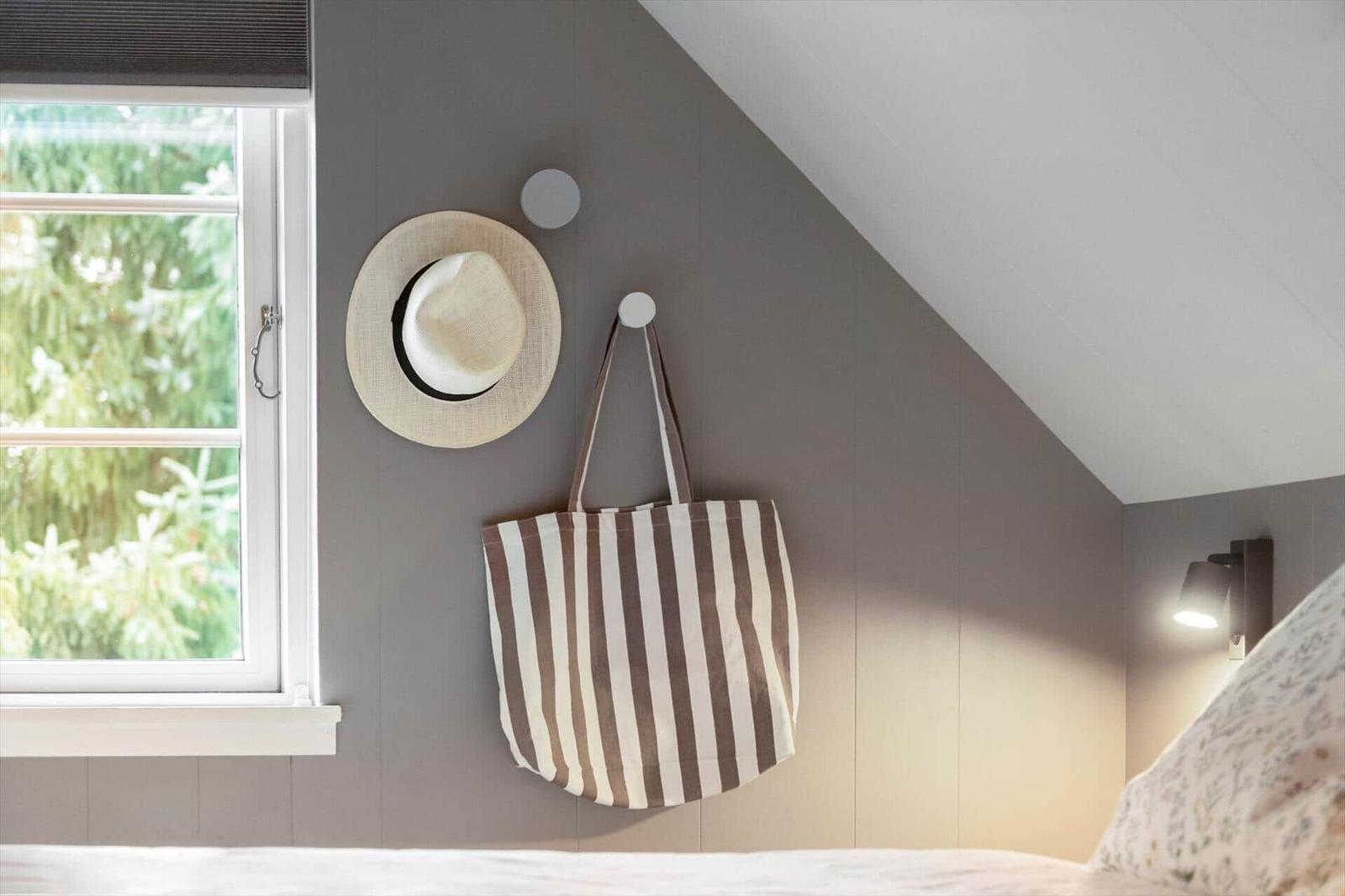 Schlafzimmer mit Dachschrägen, Fenster, Hut und Tasche an der Wand.