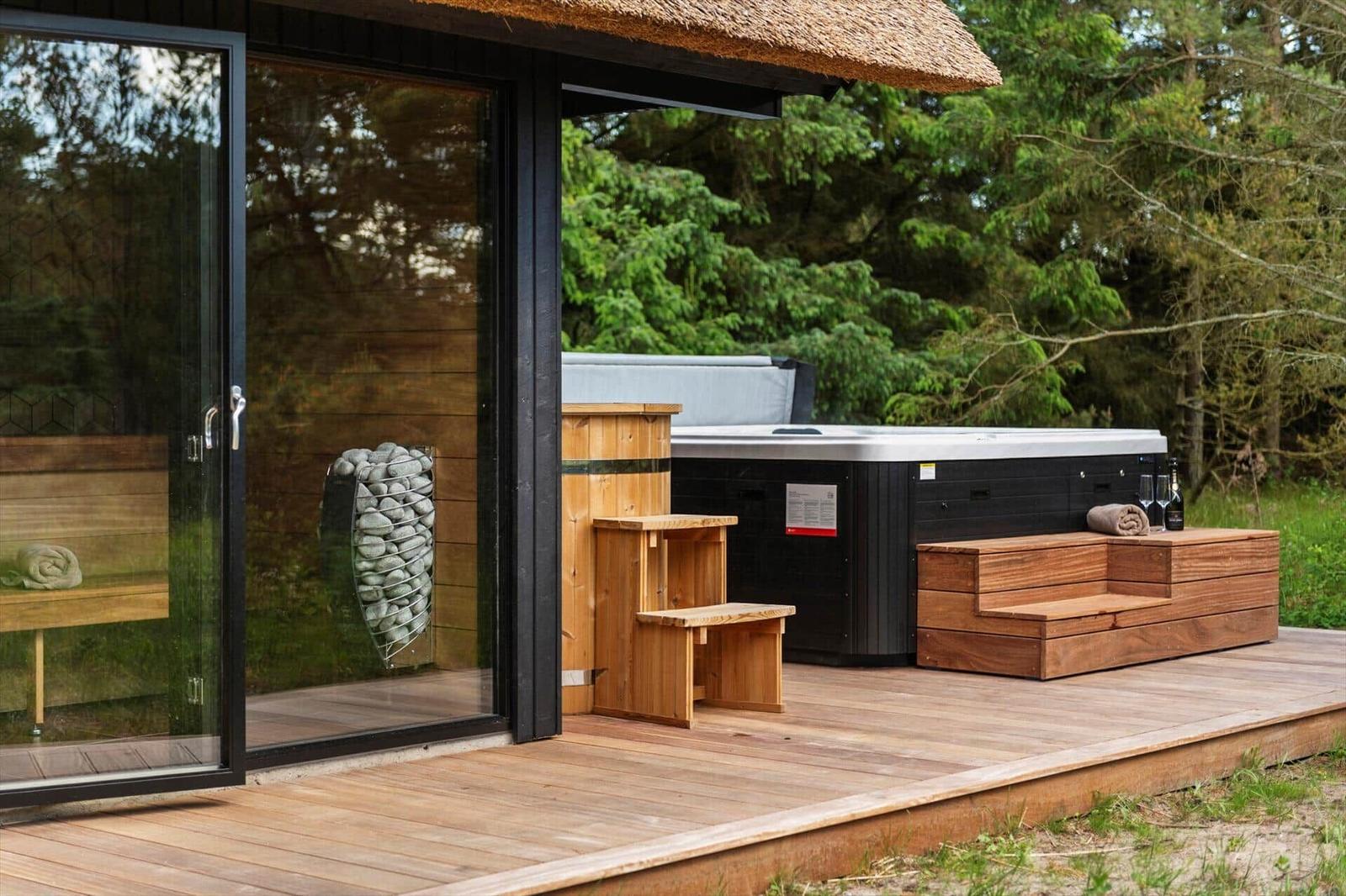 Terrasse mit Whirlpool, Holzbank und Glasfront zur Unterkunft.