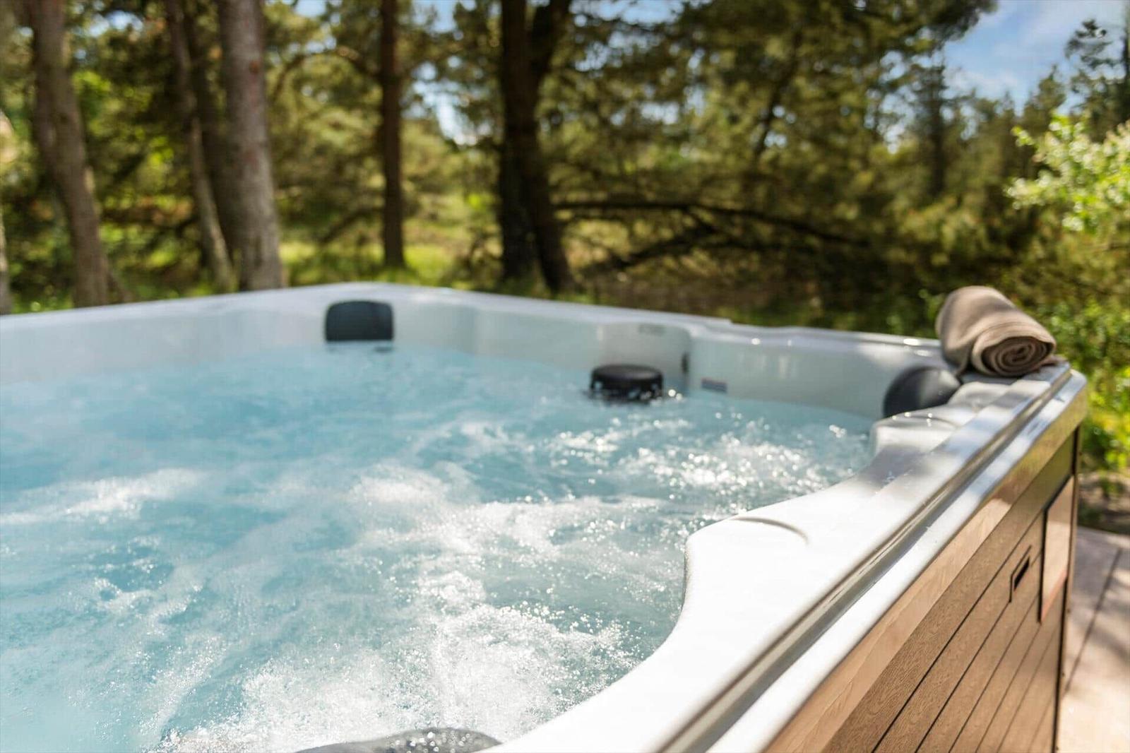 Ein Whirlpool mit blauem Wasser steht auf einer Holterrasse im Wald.