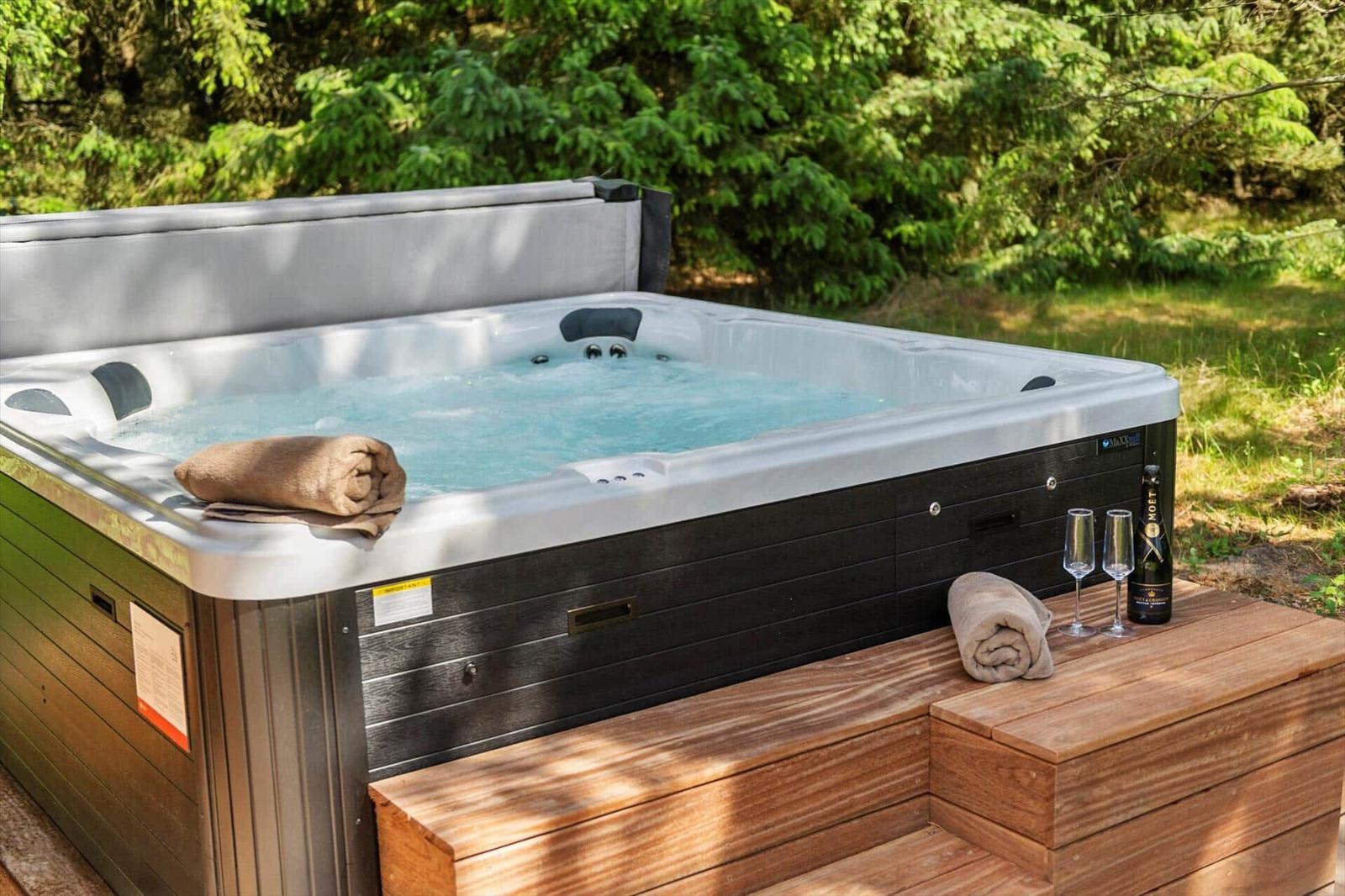 Hochwertige Whirlpool mit Holzterrasse und Getränke im Wald.