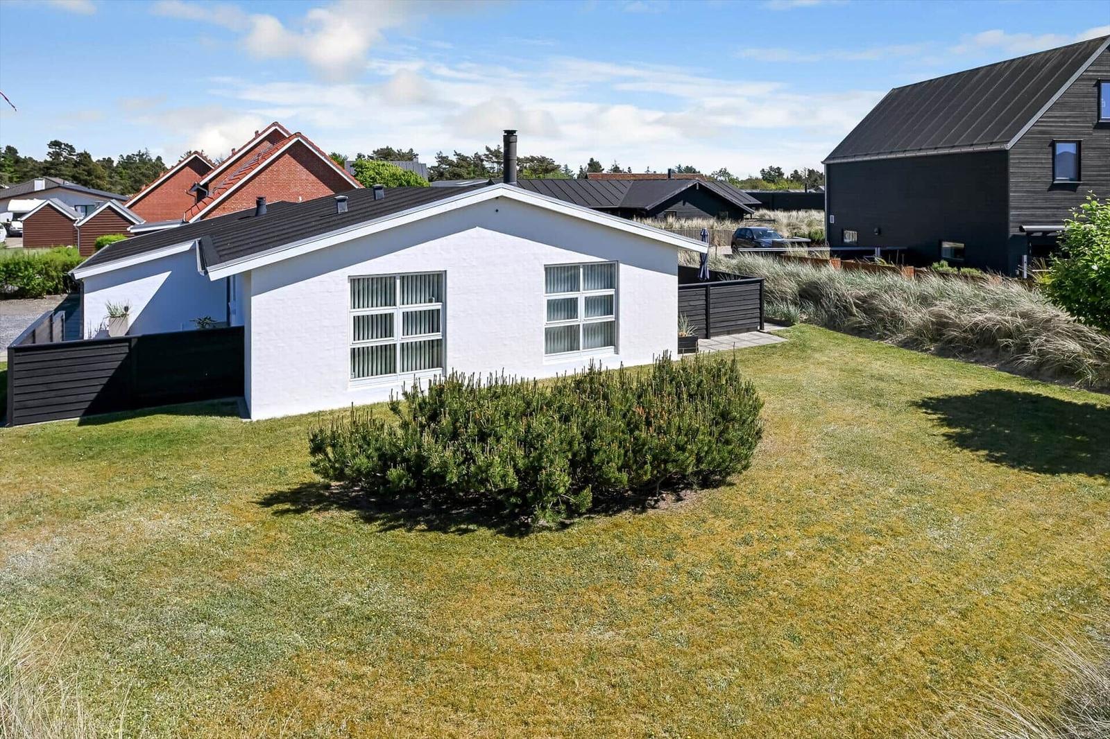 Weißes Haus mit schwarzem Dach und Garten. Neben einem modernen schwarzen Haus.