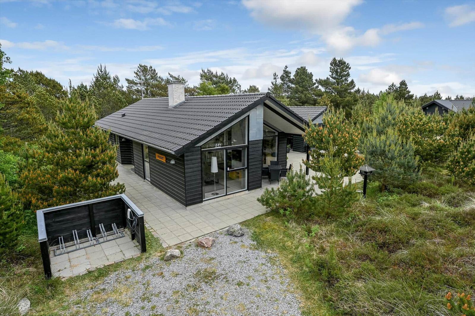 Moderne Ferienhaus mit großem Terrassenbereich und umliegenden Bäumen.