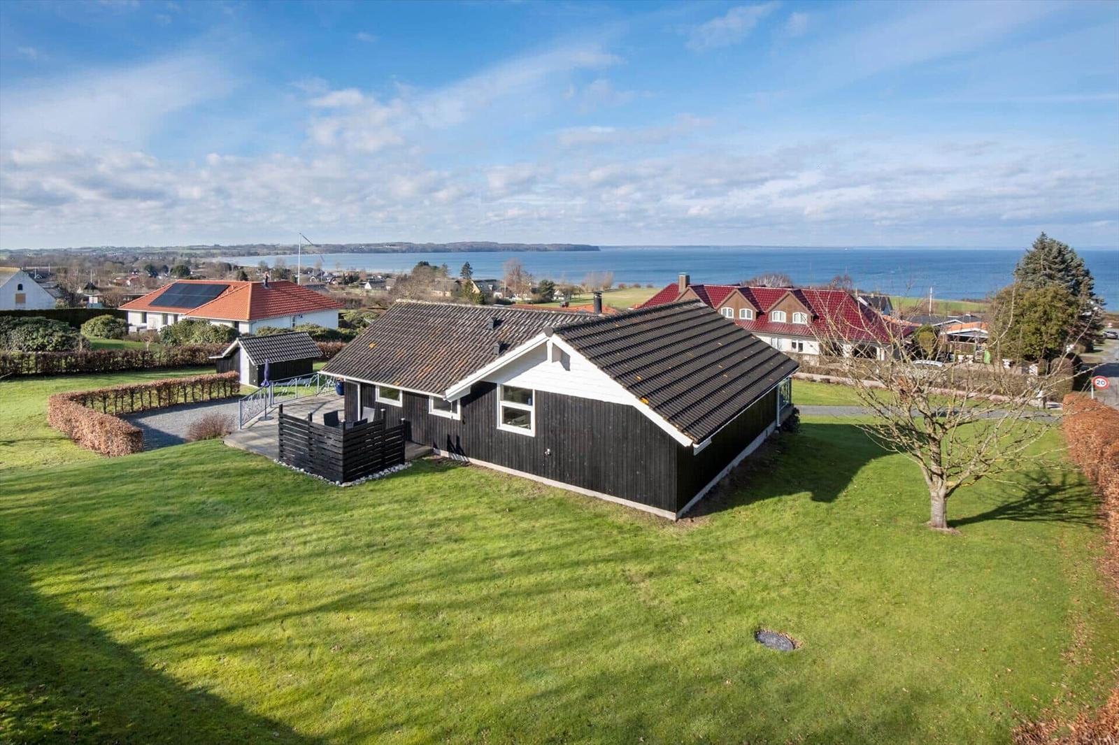 Haus mit Garten und Meerblick. Umgeben von Grün und weiteren Häusern.