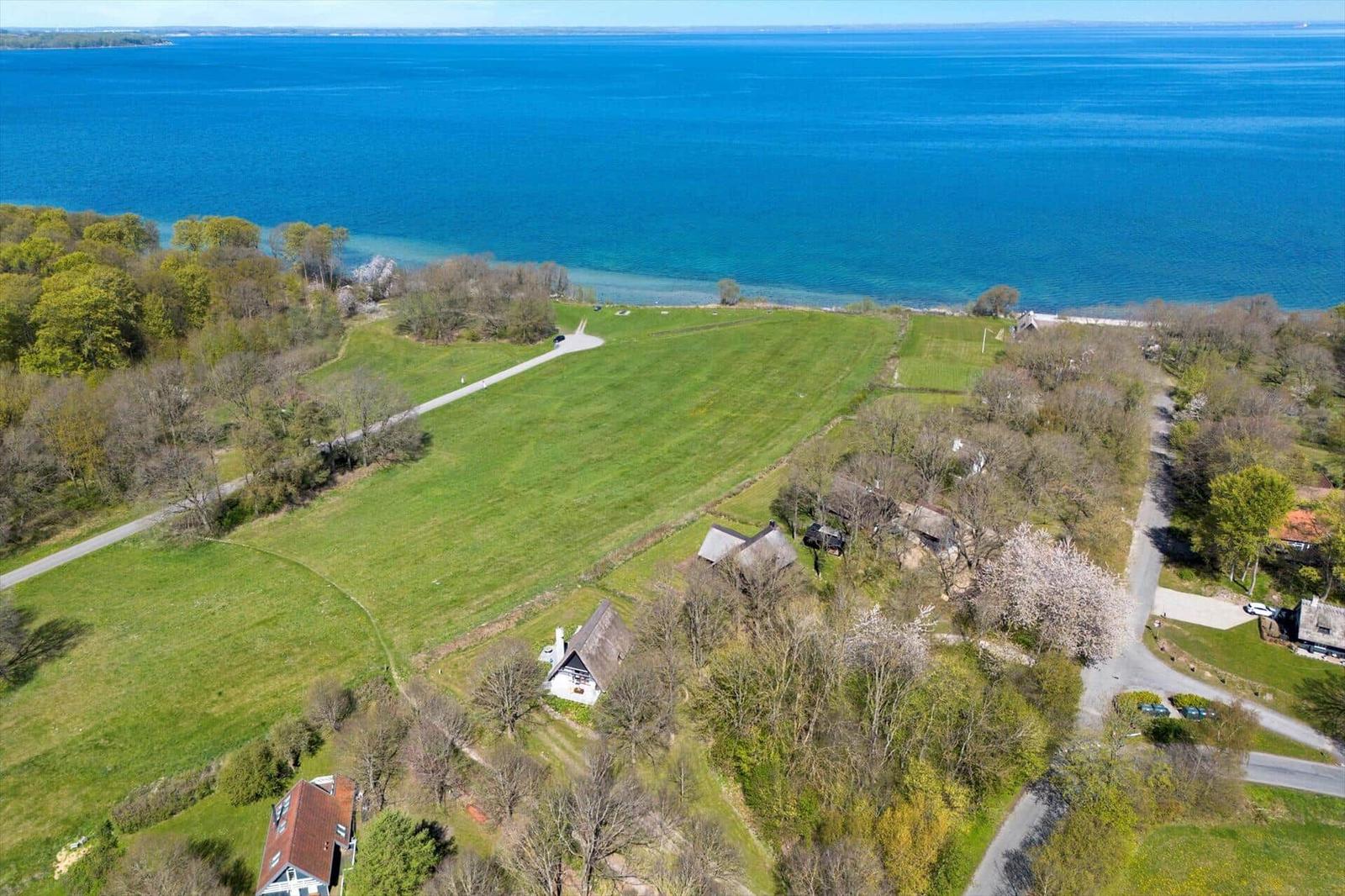 Luftbild einer grünen Landschaft mit Häusern und einem großen blauen See.