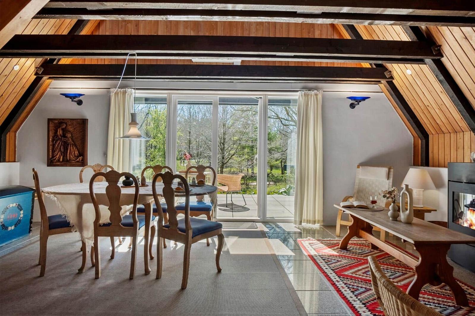 Esszimmer mit Holzdecke, Tisch mit Stühlen und Blick auf Garten