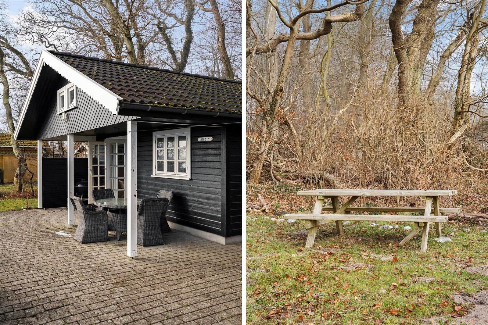 Black cabin with terrace and garden bench in the woods
