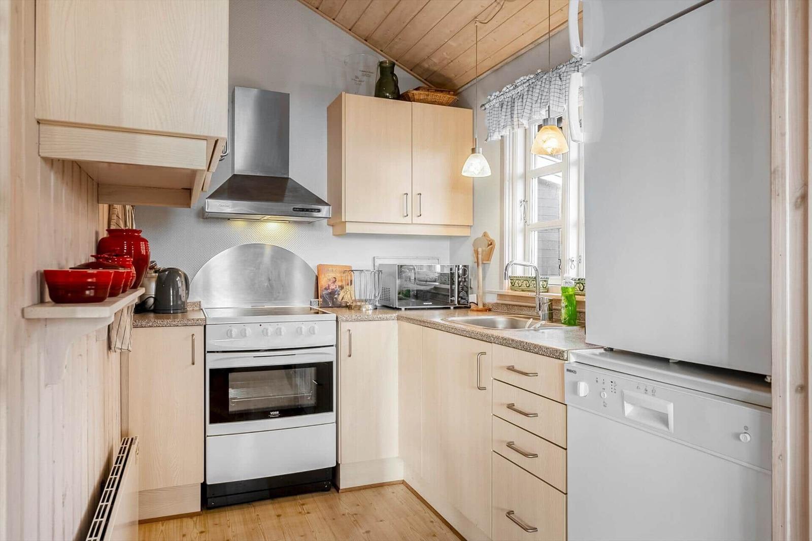 Kitchen with wooden cabinets, stainless steel stove, and window with curtain.