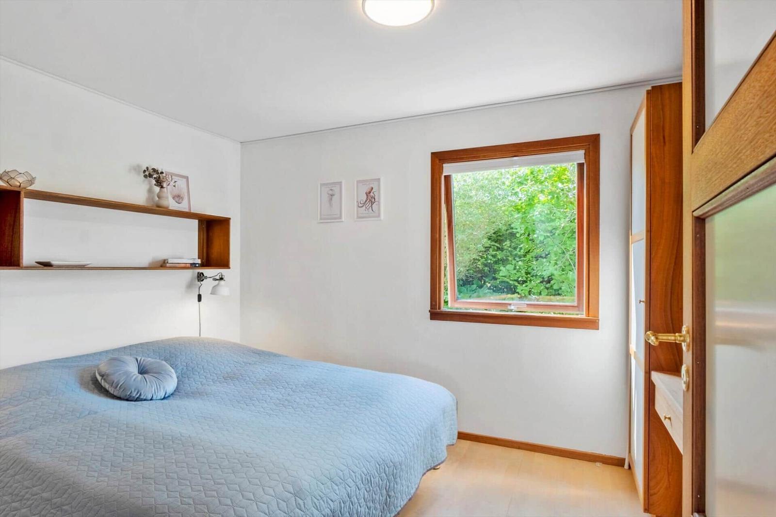 Schlafzimmer mit Bett, Fenster und Holzmöbeln.