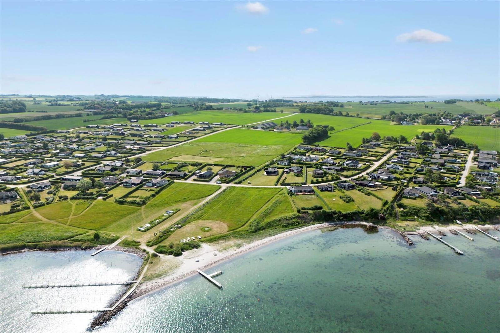 Aerial view of coastal village with green fields, houses, and water docks.