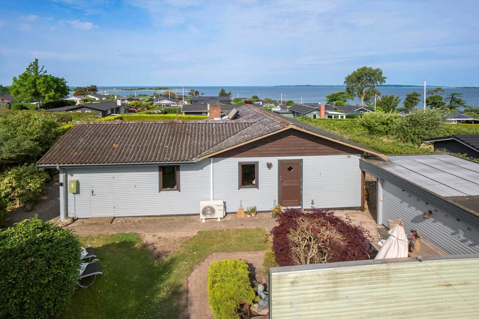 Ein Haus mit Garten und Meerblick. Terrasse, Pflanzen und Blick auf das Wasser.