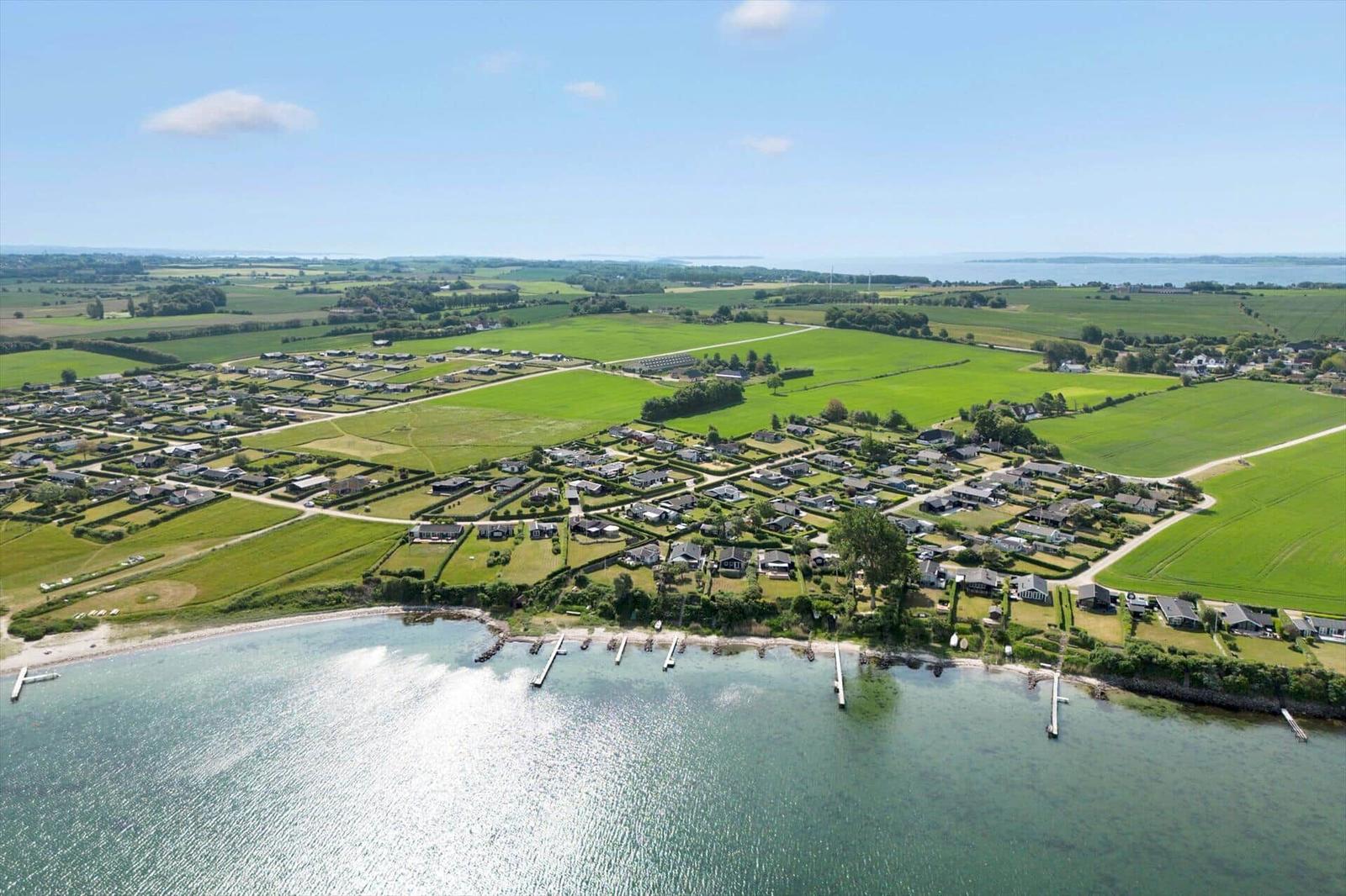 Aerial view of coastal village with green fields and water access.