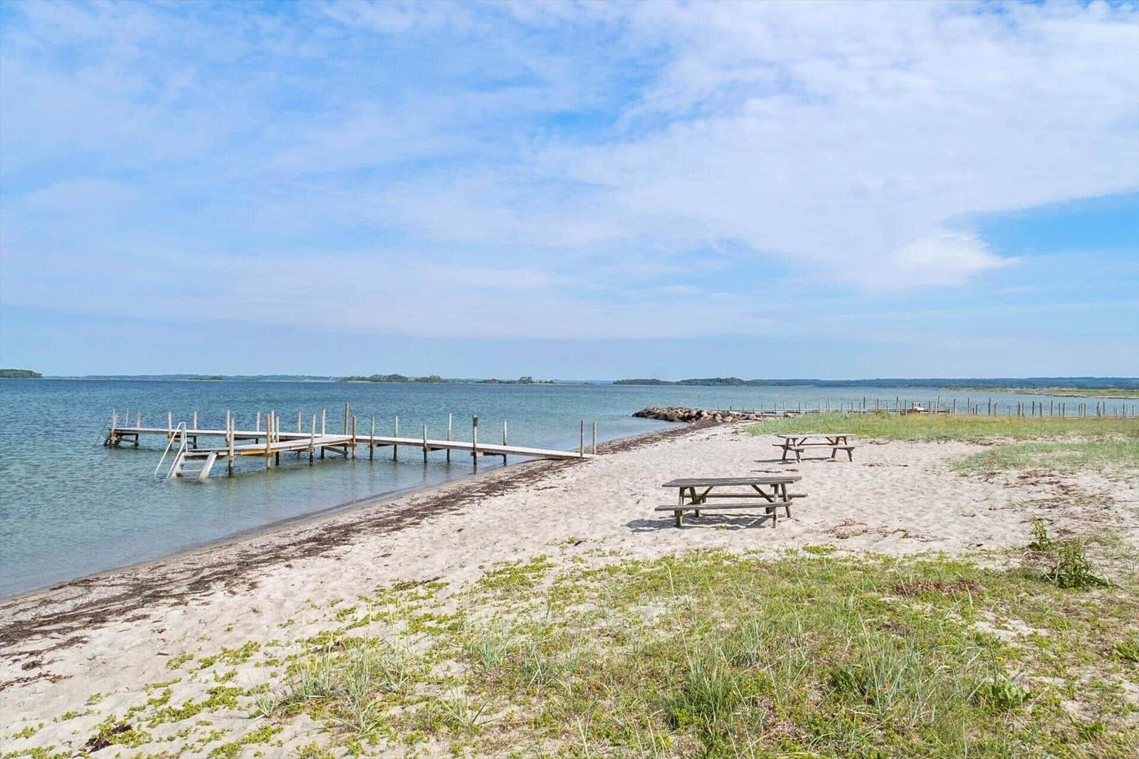 Strand mit Holzsteg und Picknicktischen am Wasser