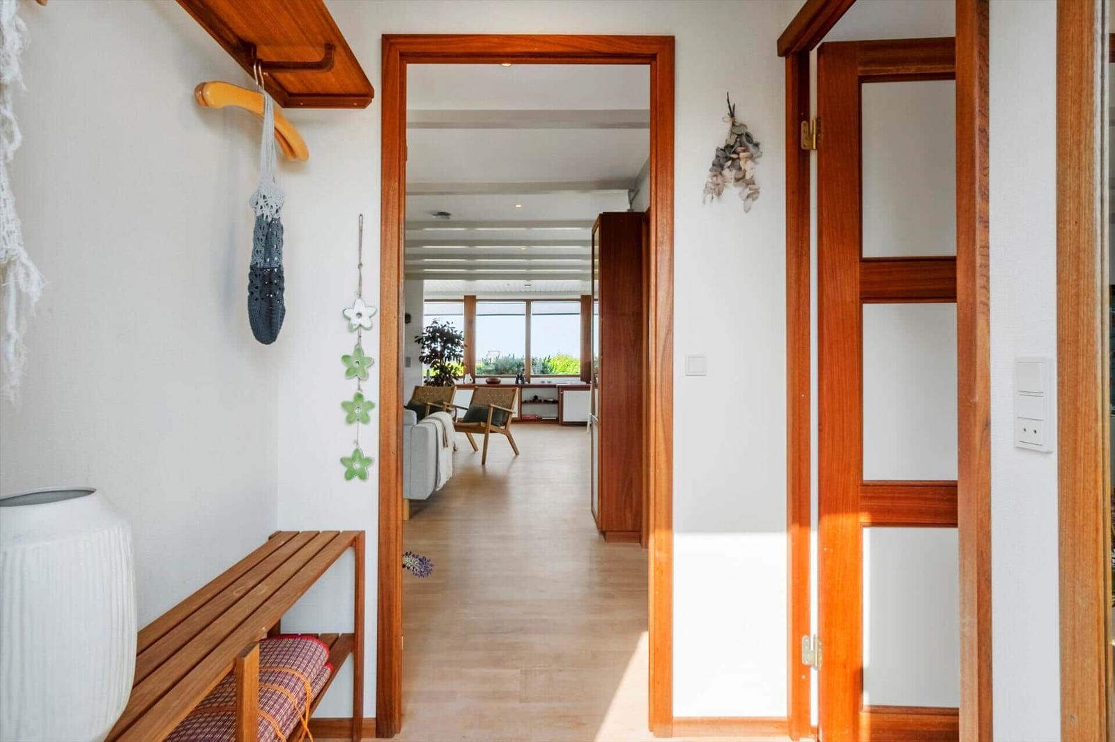 Haus mit Holzfußboden und Tür, Blick in Wohnzimmer mit Sofa und Stühlen.