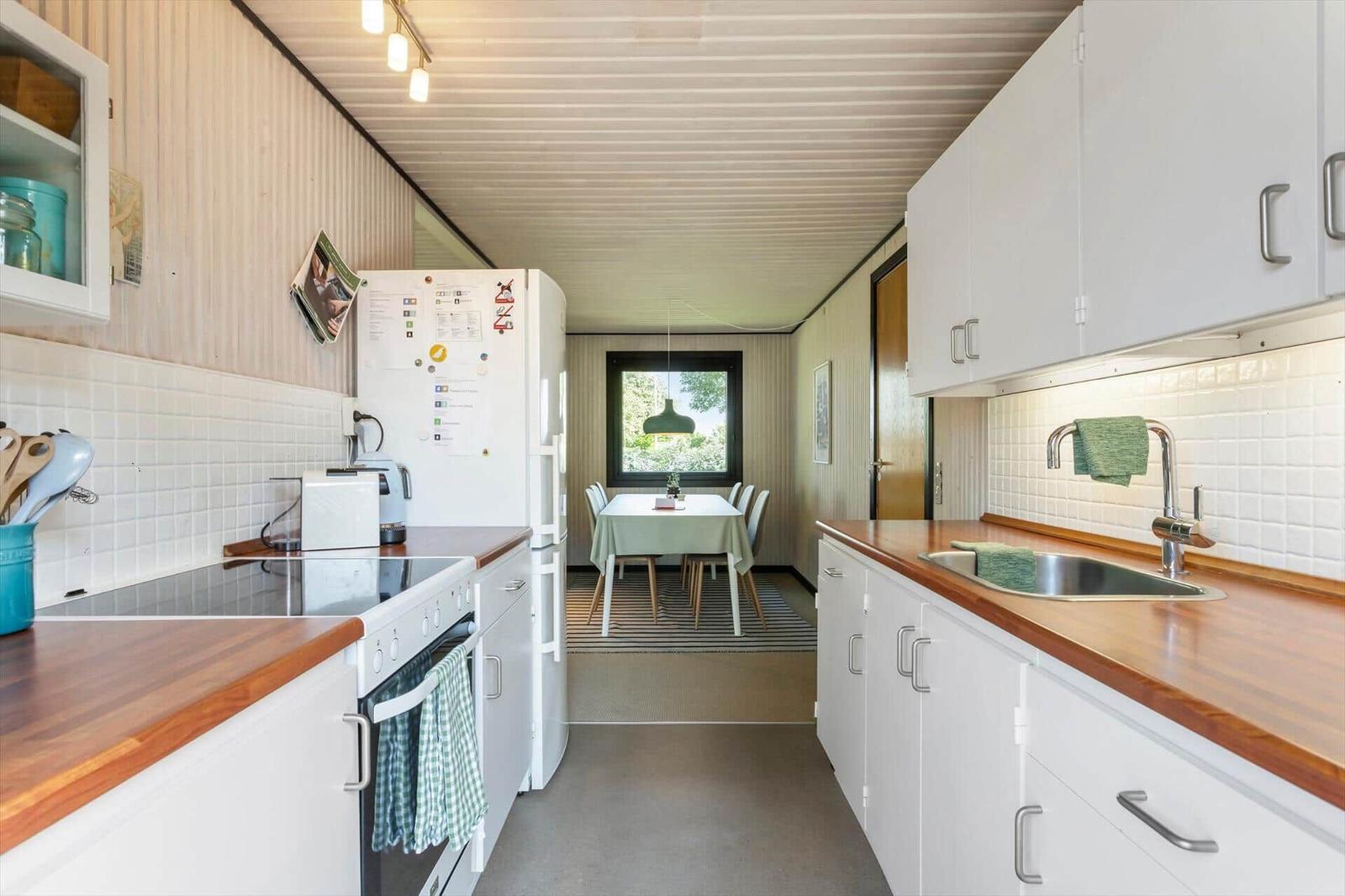 Kitchen with white cabinets, wooden countertops, and view into dining area with table and chairs.