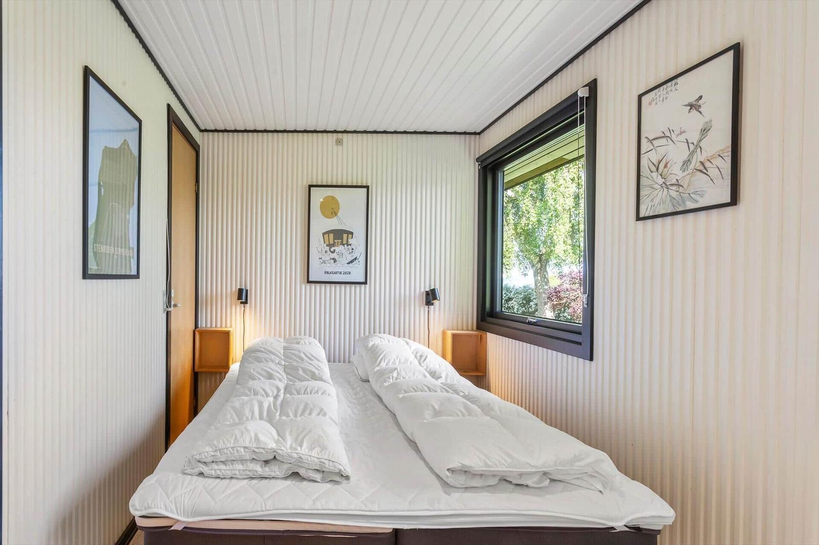 Bedroom with bed, window, and wall pictures.