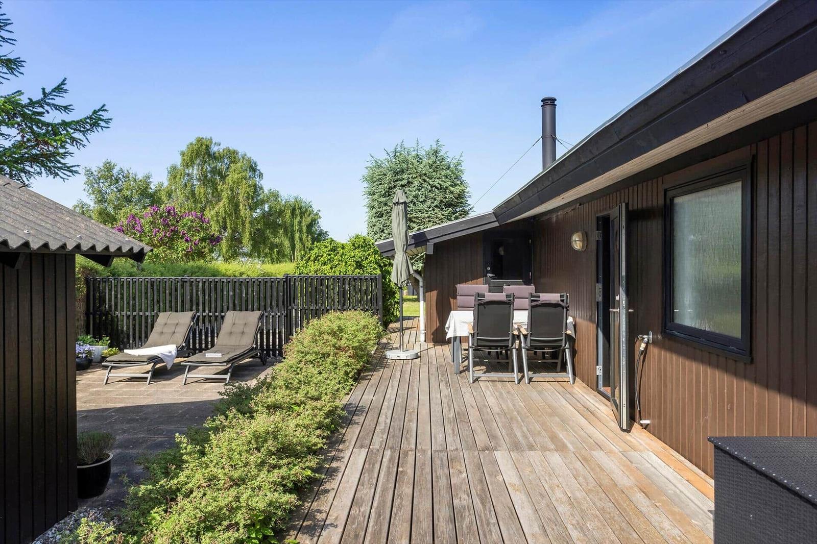 Deck with lounge chairs and table. Backyard with fence and trees.