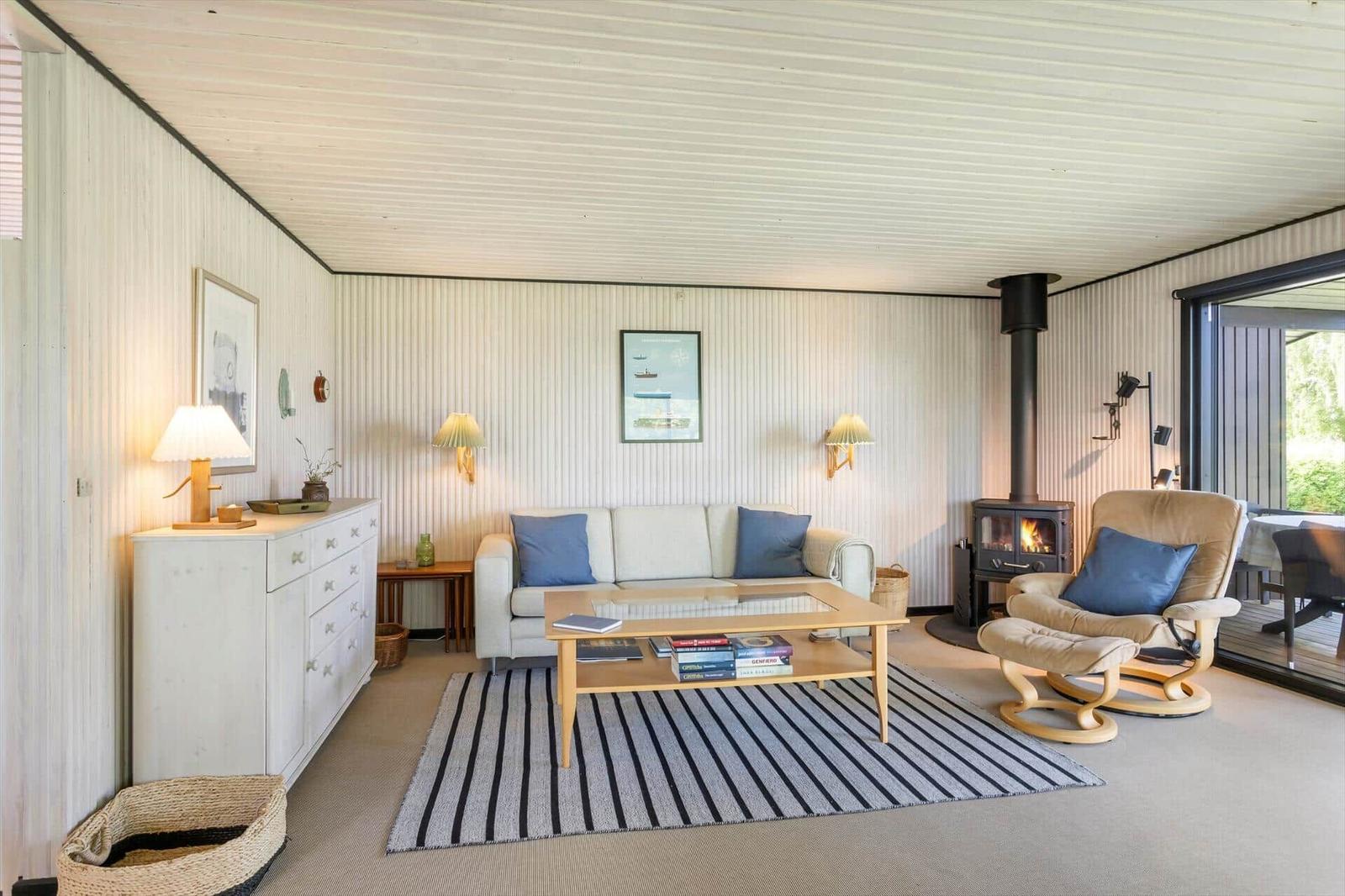 Living room with sofa, armchair, fireplace, and glass door to terrace.