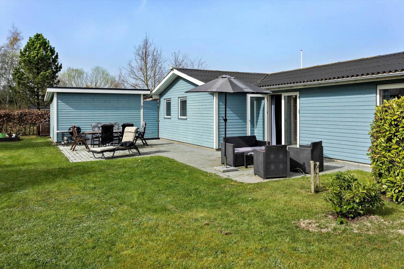A blue holiday home with garden, patio, and outdoor seating areas.