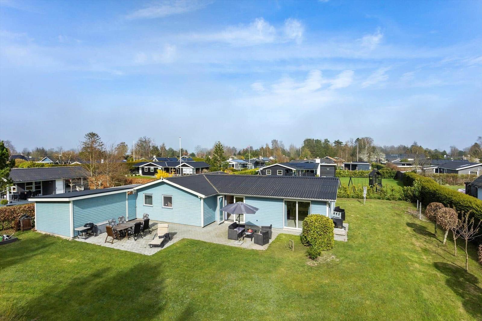 A light blue holiday home with a large garden and outdoor seating area.